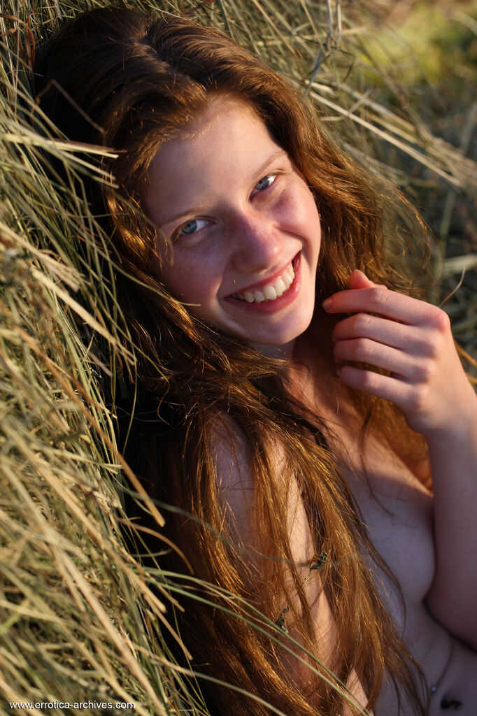 Red-haired beauty posing seductively on a pile of hay with her perky ass on display - Nicole K
