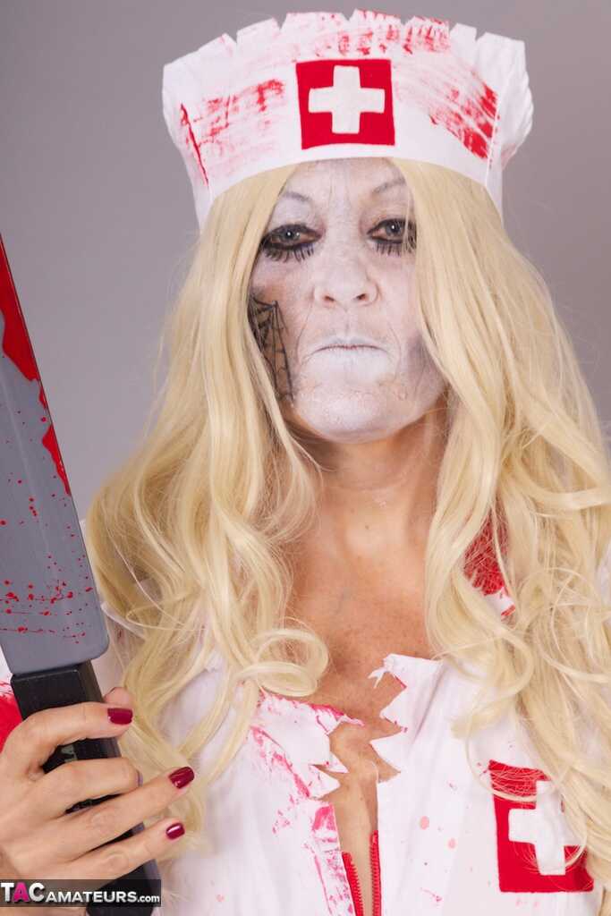Old blonde amateur Savana removes a nurse uniform during a cosplay scene - Savana