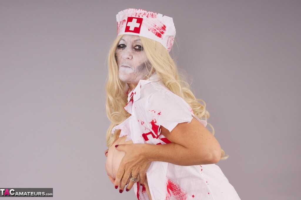 Old blonde amateur Savana removes a nurse uniform during a cosplay scene