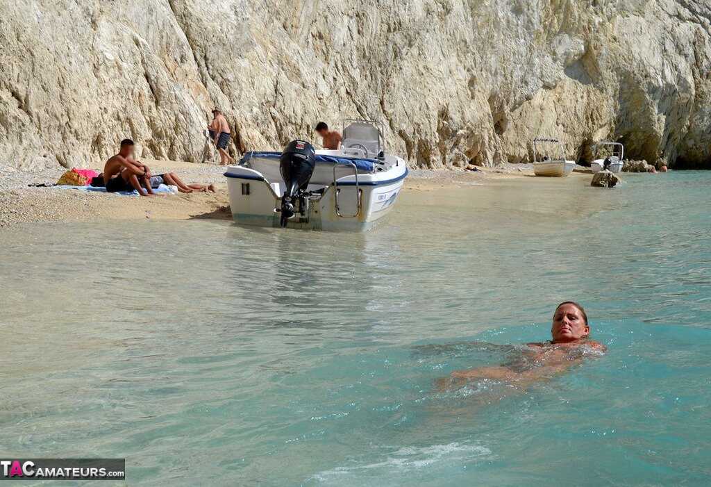 Mature Beach Slut Gets Naked and Wet: Huge Boobs on Display in the Sand!