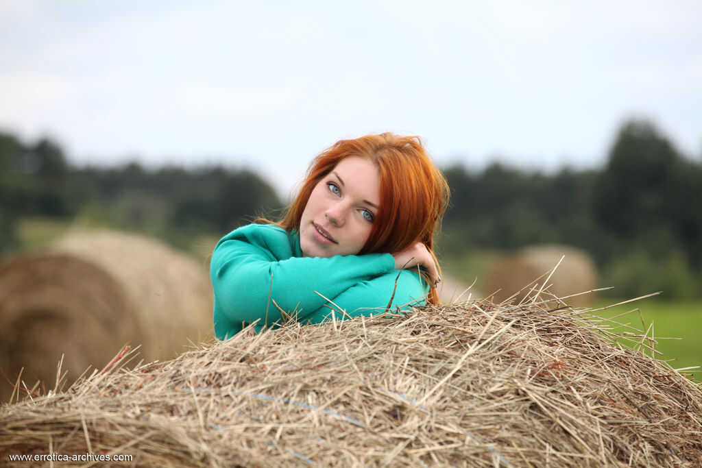 Natural redhead Amber A spreads her big ass on round bale of hay in the outdoors, showing off her naked teen body with a beautiful pussy and long legs.