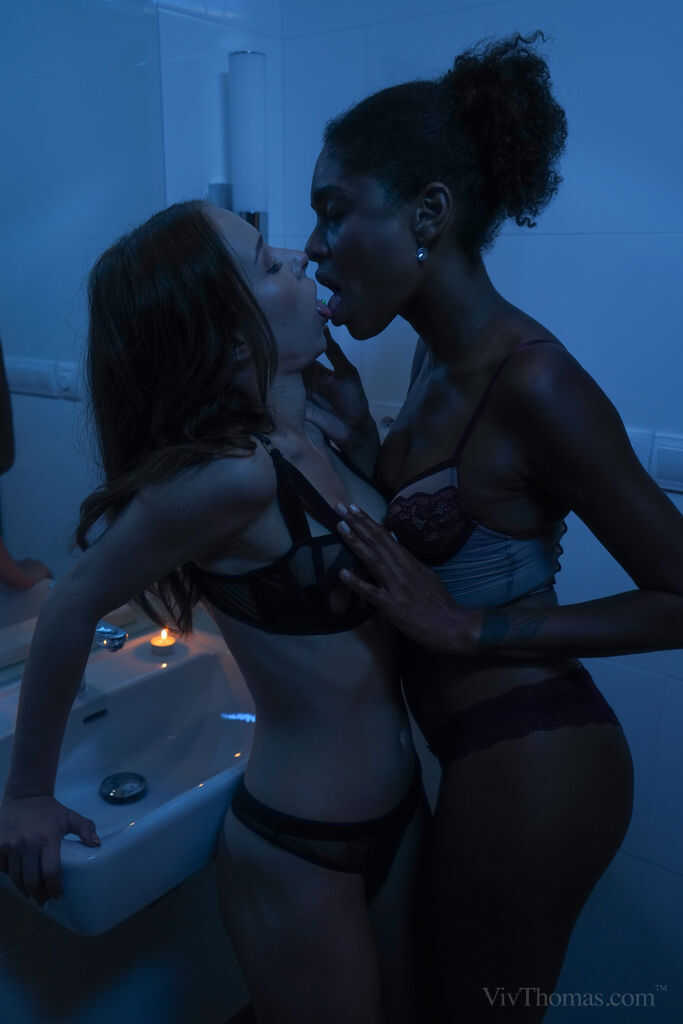 Lesbian Luna and Nata get dirty on a bed in the shadows, with their black bodies glistening with sweat 