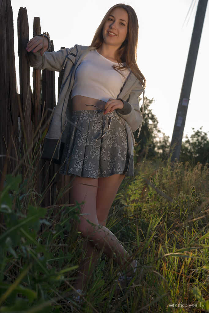 Long haired teen Hrizantema strips to her sneakers by a tree in a field and bends over for the camera to show off her tigh...