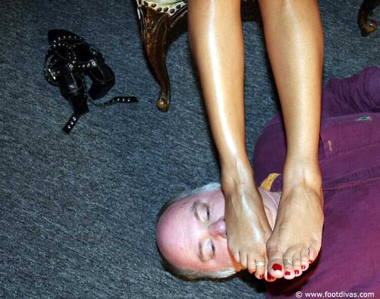 Caucasian female rubs her feet all over an old man's face - 