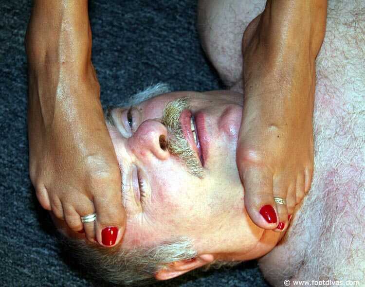 Caucasian female rubs her feet all over an old man's face - 