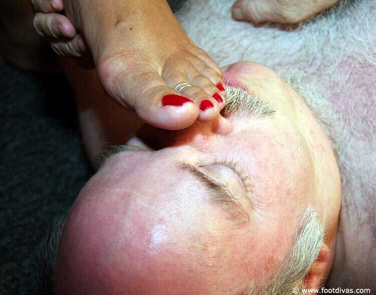 Caucasian female rubs her feet all over an old man's face - 