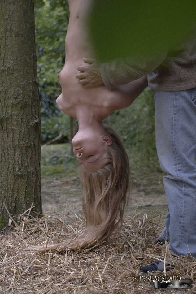 Young Cayenne blonde teen suspended upside down in the woods gets her hair pulled by a dominant nudist. - Cayenne Klein