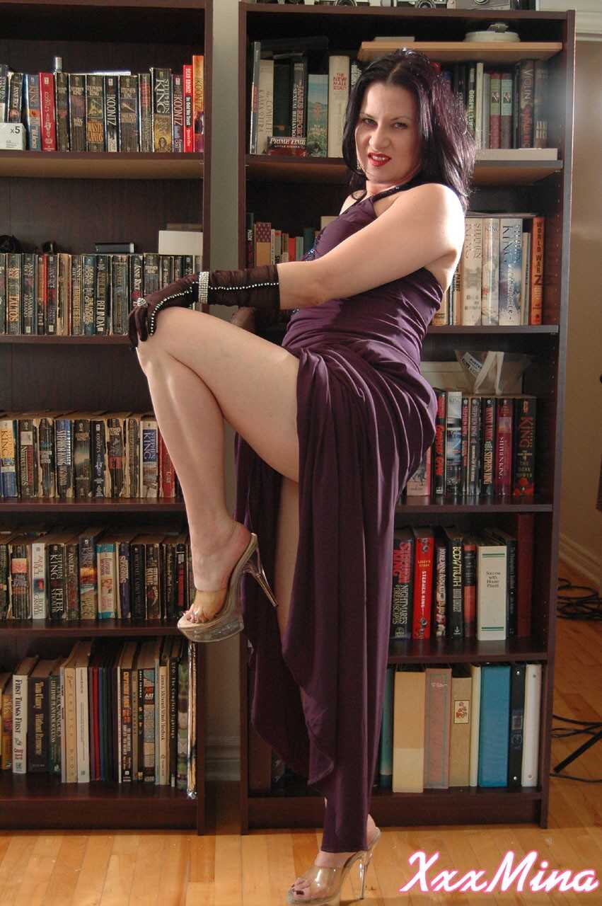 Mature Mina Gorey strips naked in gloves and heels afore a bookcase to show off her sexy small tits! - Mina Gorey