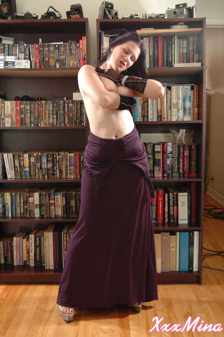 Mature Mina Gorey strips naked in gloves and heels afore a bookcase to show off her sexy small tits! - Mina Gorey