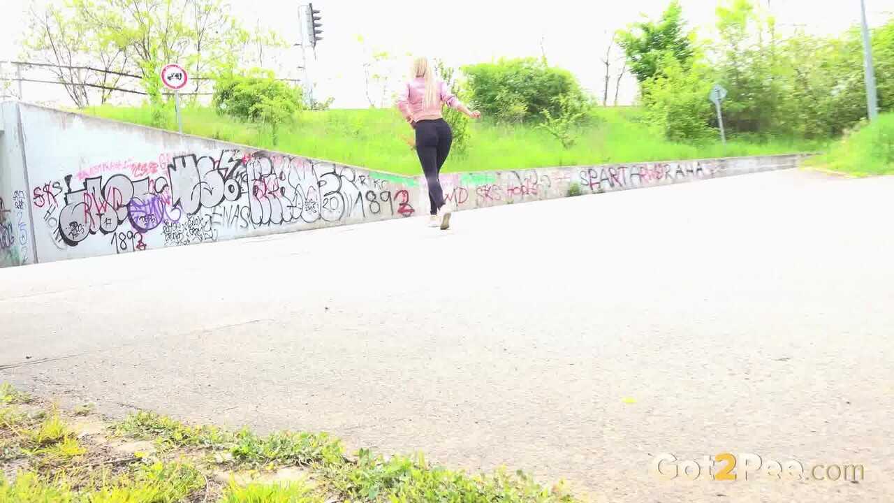 Blonde beauty Emily Bright can't hold it in any longer as she desperately pulls down her leggings beside a car for an urgent pee