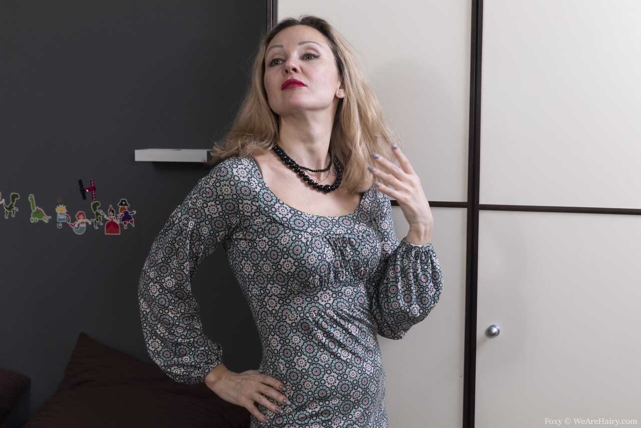 Blonde MILF Foxy shows off her hairy pussy while partially disrobing in lingerie and high heels. - Foxy
