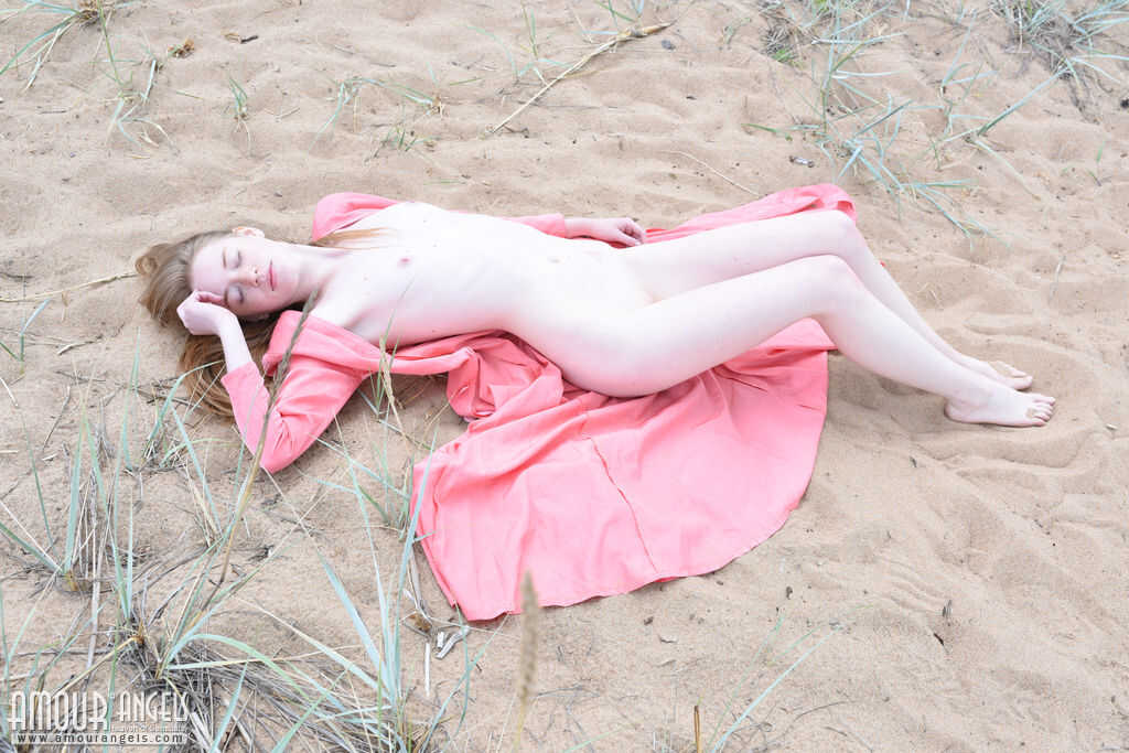 Fair-skinned teen Gerda gets naked on the beach, letting her body glisten in the sunlight.