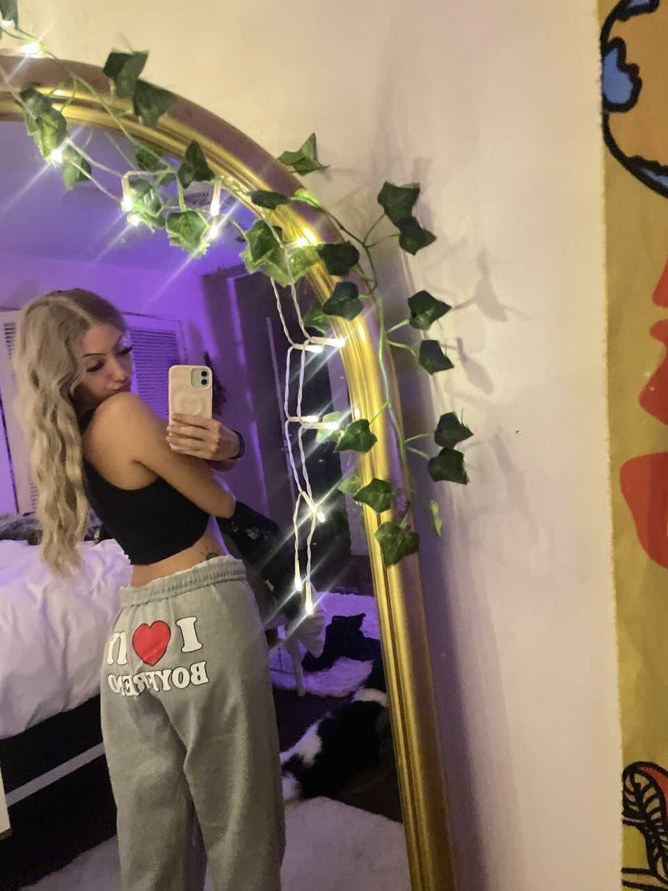 Skinny OnlyFans model Blondie Alexis poses provocatively in a solo mirror selfie, teasing her nerdy glasses-wearing follow...