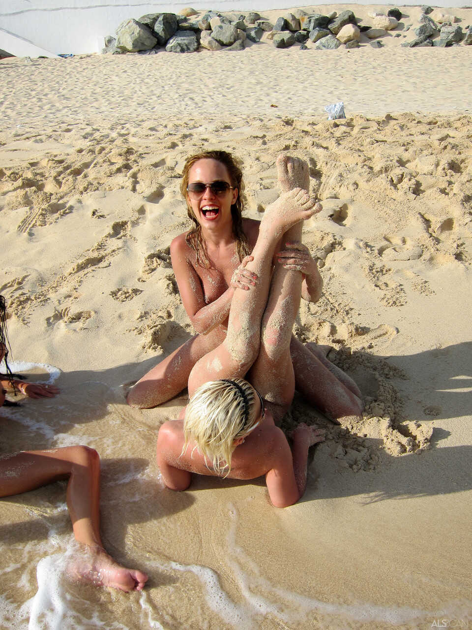 Blonde lesbian Bibi Noel and her slutty GFs frolic on the beach while naked, exposing their tight shaved pussies for all to see. 