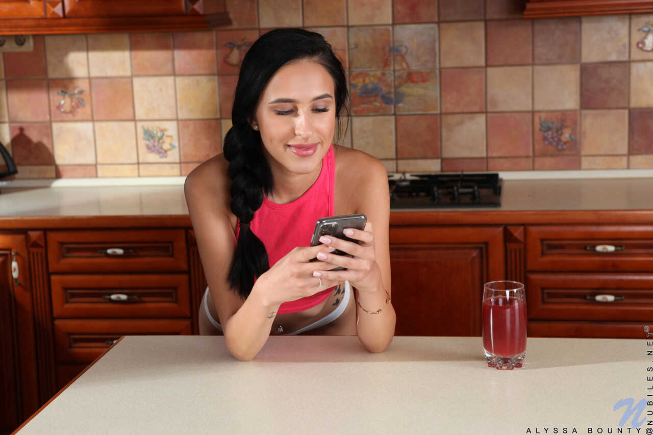 Raven-haired Alyssa Bounty spreads her legs on the kitchen counter, revealing her slim figure and pink pussy - Alyssa Bounty