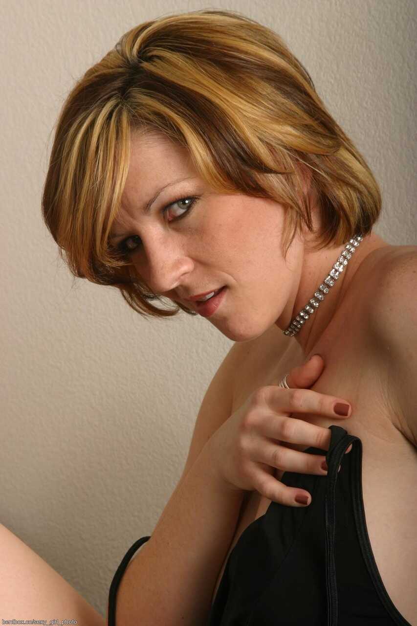 Sexy slender mom Carly posing seductively in a tight corset, panties and stockings - Carly