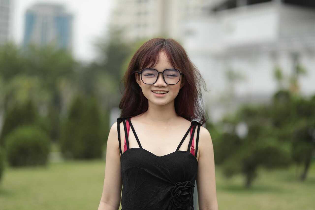 Sexy Asian Girl in Bentbox Posing with Red Glasses in an Outdoor Park