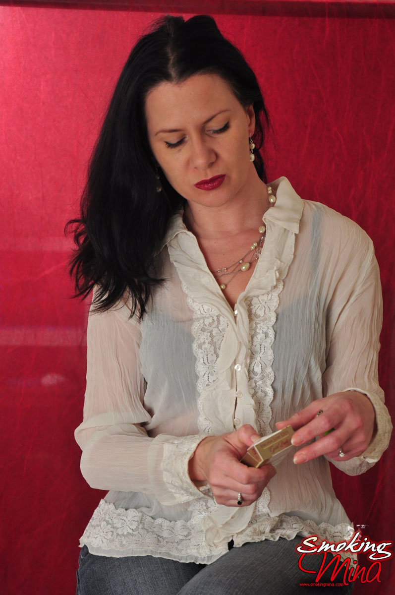 فتاة سمراء ببلوزة شفافة تدخن بشكل مثير