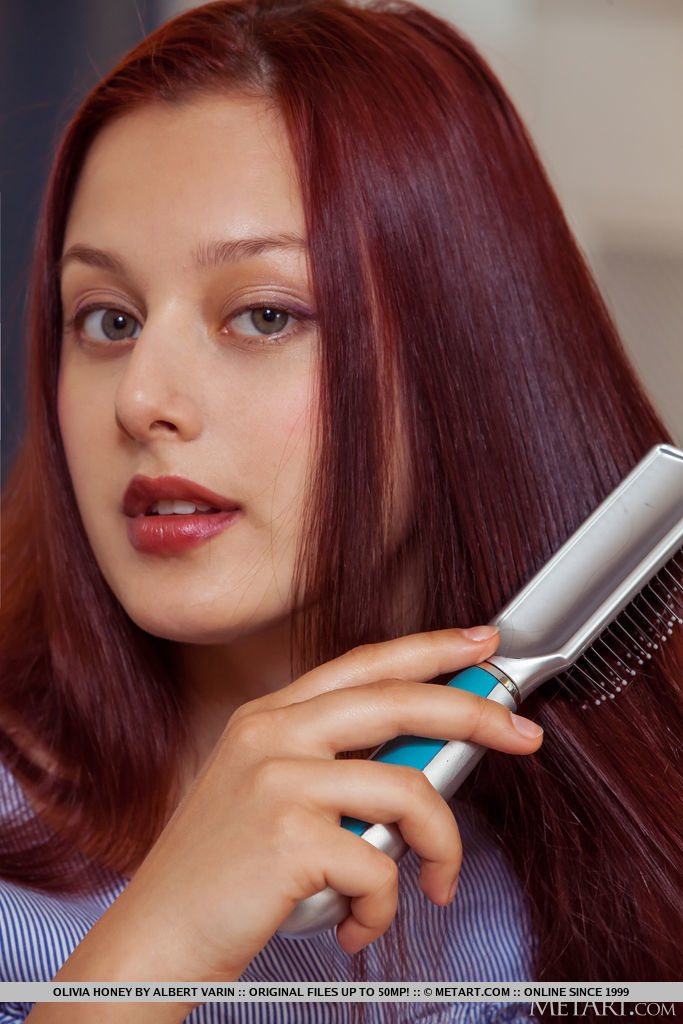 युवा लाल बालों वाली ओलिविया हनी पूरी तरह नग्न होने से पहले लंबे बालों को ब्रश करती है