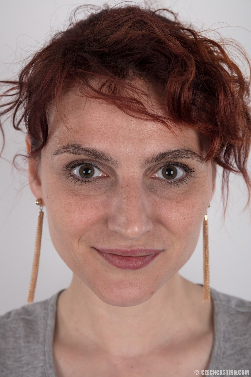 امرأة حمراء الشعر الموشومة كاميلا تقف عارية بعد خلع ملابسها خلال عمل فردي