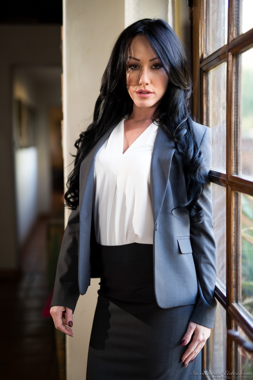 黒髪の女性がブレザーとスカートを脱いで窓際で裸でポーズを取る