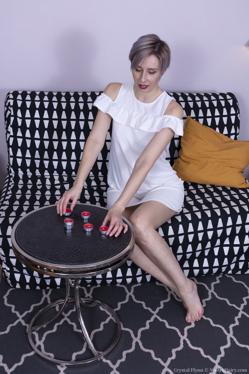 紫の髪のアメリカ人クリスタル・フリンがソファで毛深い股間を露出