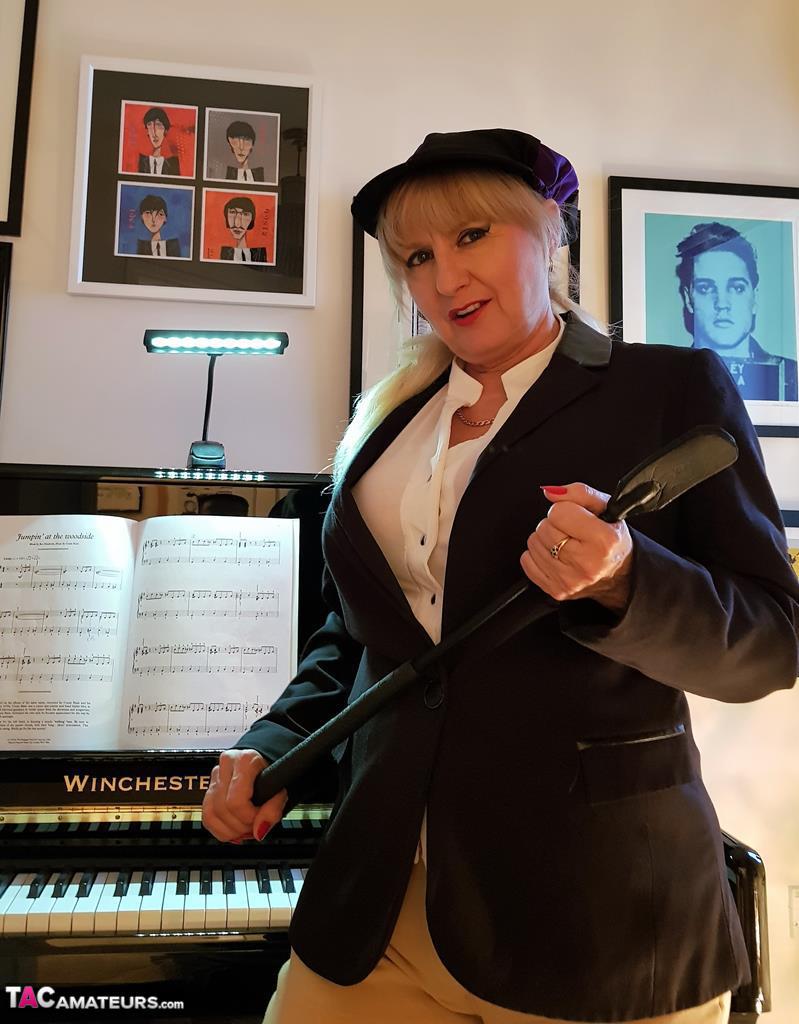 شقراء ميلف في حذاء أسود تنزع سراويل ركوب الخيل لإظهار مهبل