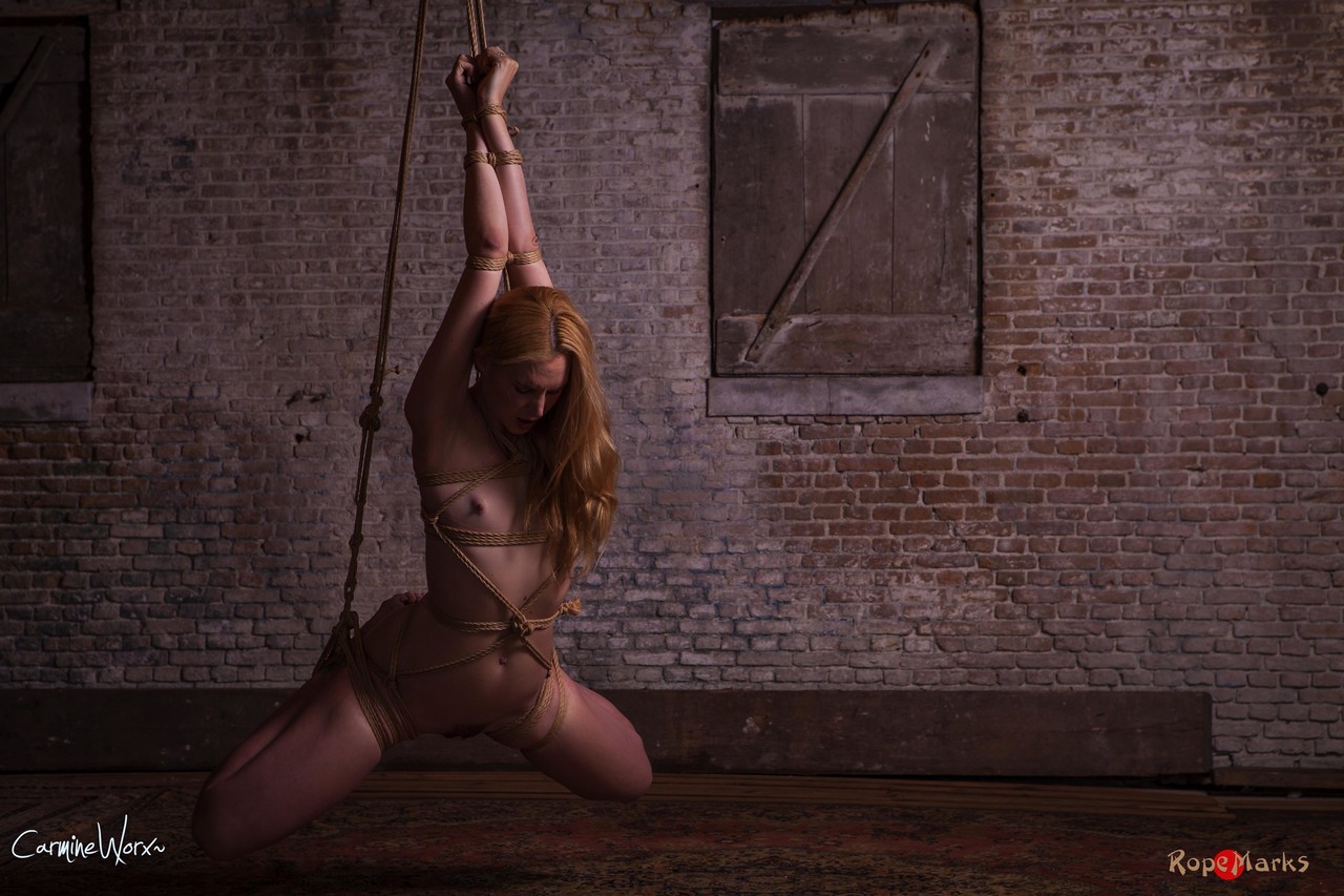 छत से नंगी बाँधी हुई सुनहरे बालों वाली औरत लटकी हुई