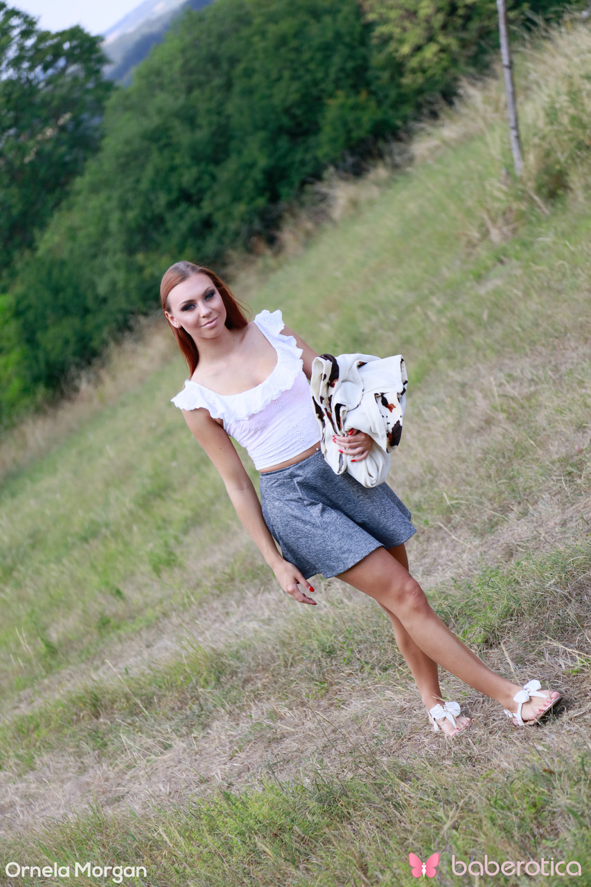 लंबी लाल-बालों वाली सुंदरी ओर्नेला मॉर्गन बाहर नंगी होकर खिलौने से खेलती है