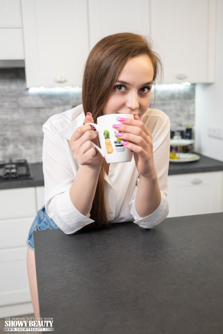 جولي الجميلة الشابة العارية عرض إزالة الملابس في المطبخ مع القهوة