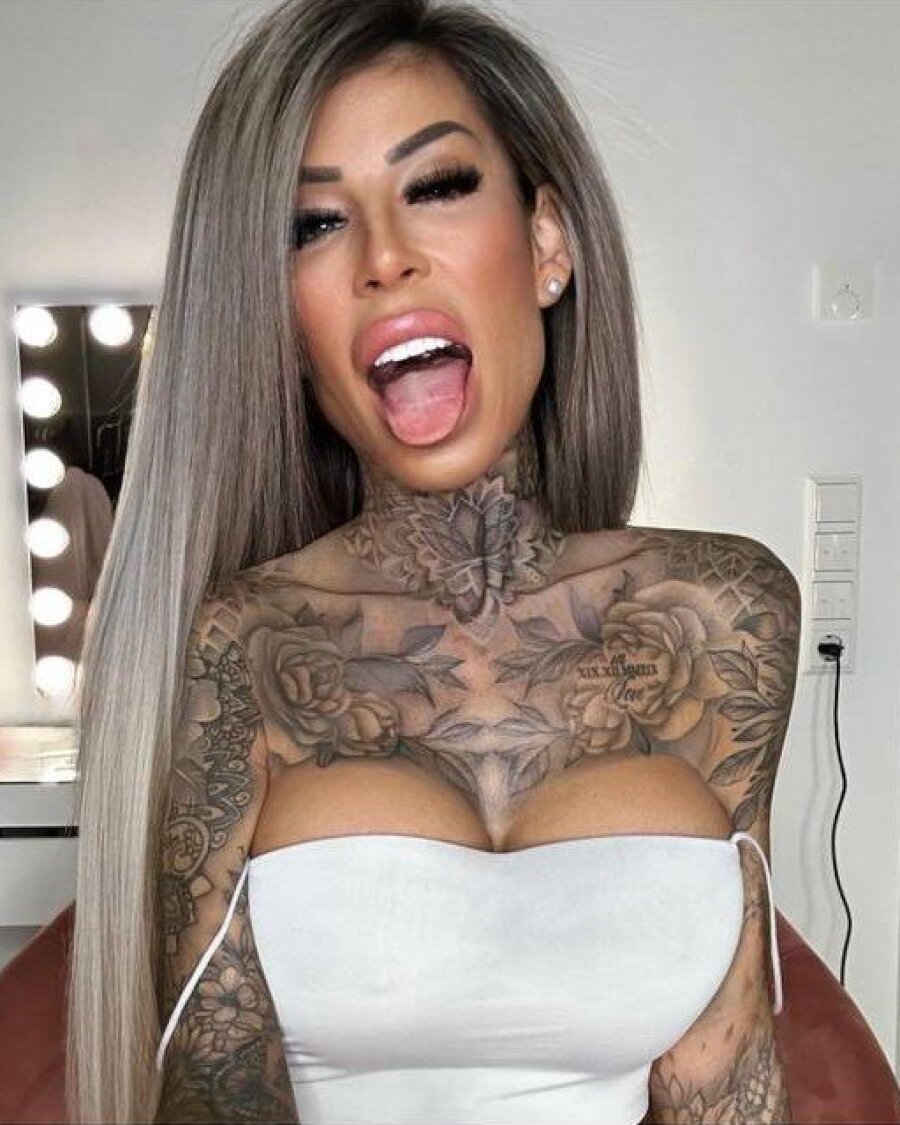 タトゥーの入った素人美女がピンクの網タイツでポーズを取り、セクシーな脚と胸元をアピール