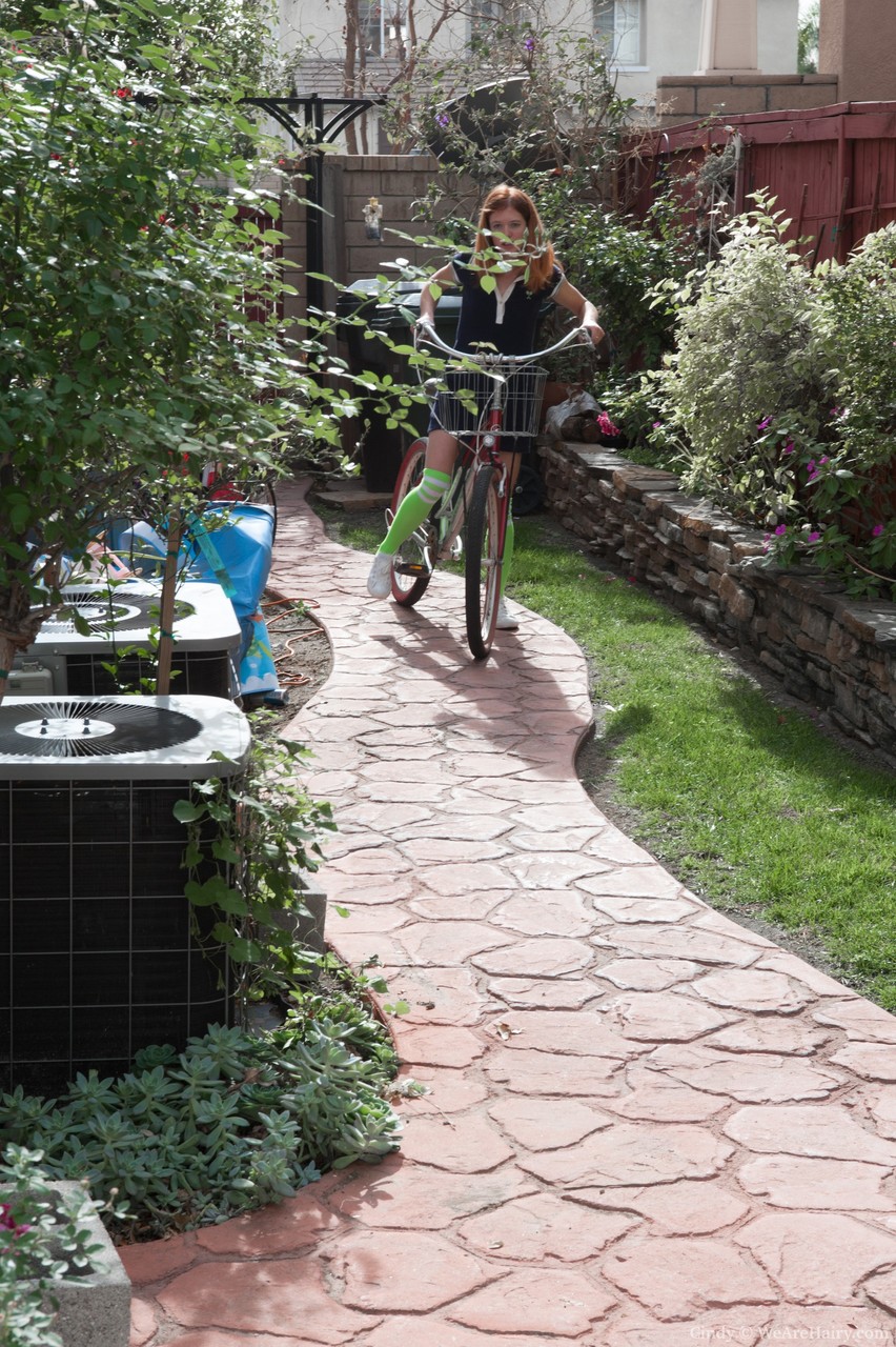 लाल बालों की किशोरी सिंडी बगीचे में कपड़े उतारती है और घने जंगल को दिखाती है