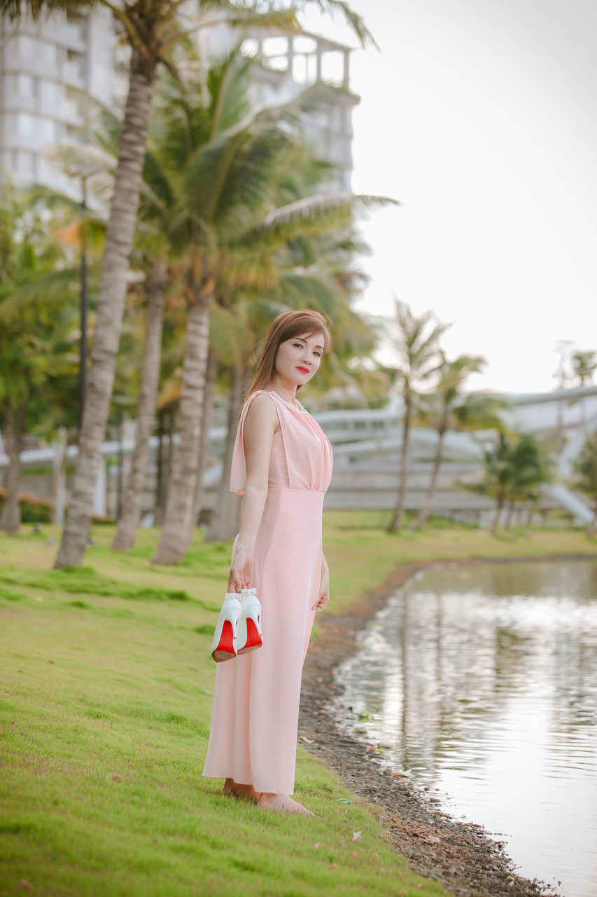 セクシーなアジア人モデルがエレガントなドレスを着て公共の場でポーズをとる