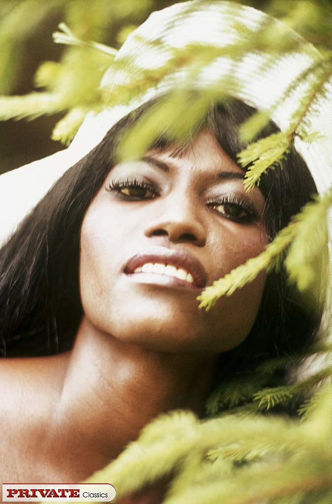 サンハットとビキニを着た黒人女性が茂みに入って裸でポーズを取る