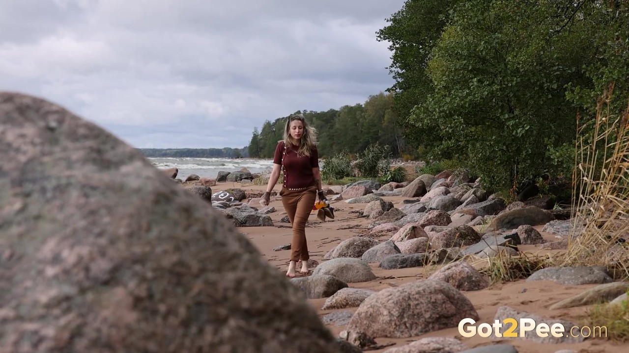 凯蒂·迪倚在海滩的一块巨石上，急需一泡尿