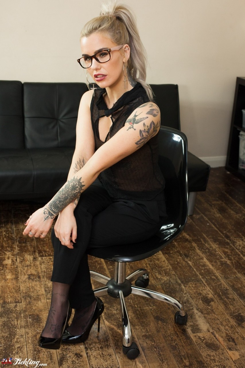 完全に服を着た金髪のジェイドがハイヒールを脱ぐ