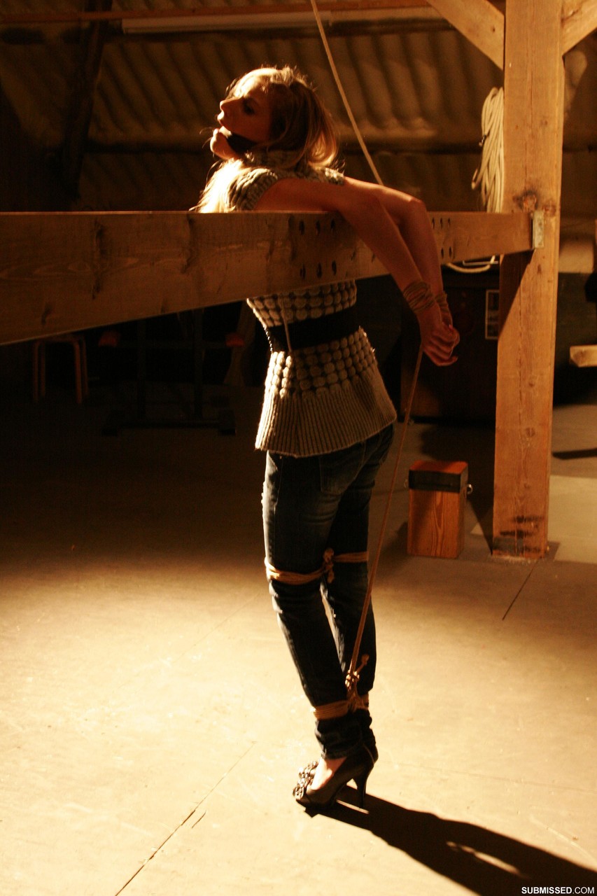 सुंदर सुनहरे बालों वाली लड़की अपने कपड़े पहने हुए गैग और रस्सियों के खिलाफ संघर्ष करती है